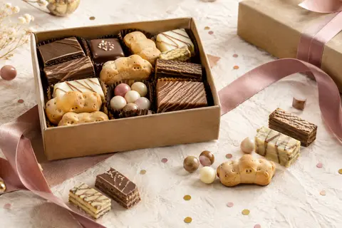Coffret en carton recyclé avec un assortiment de gaufrettes, biscuits et confiseries chocolatées pour un anniversaire.