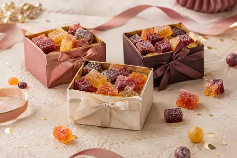 Trois ballotins de pâtes de fruits aux six parfums, présentés dans un décor d’anniversaire sobre.